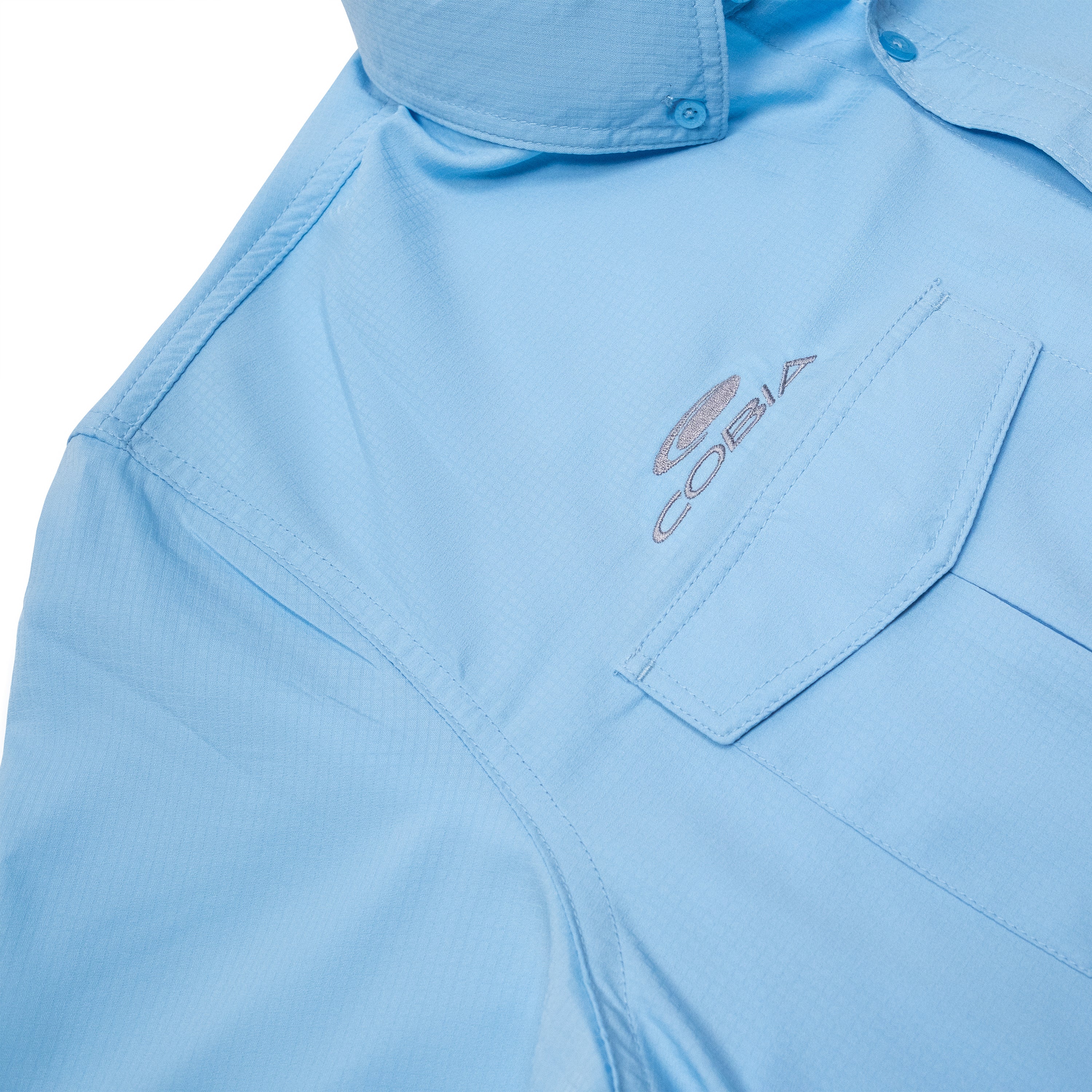 Close-up of a light blue button-up shirt with a grey Cobia logo.