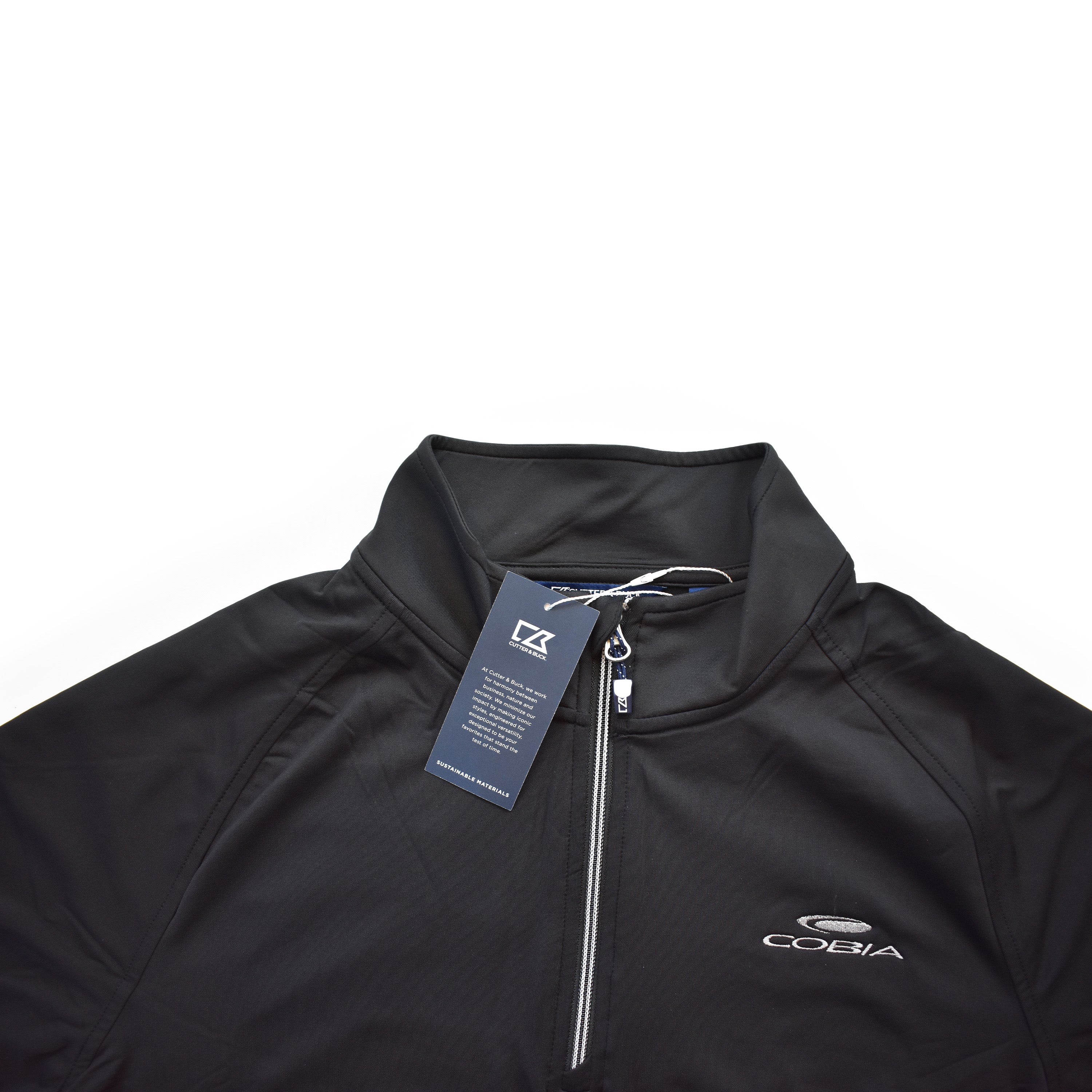 Black athletic zip-up shirt with a tag and a white cobia logo on the chest.