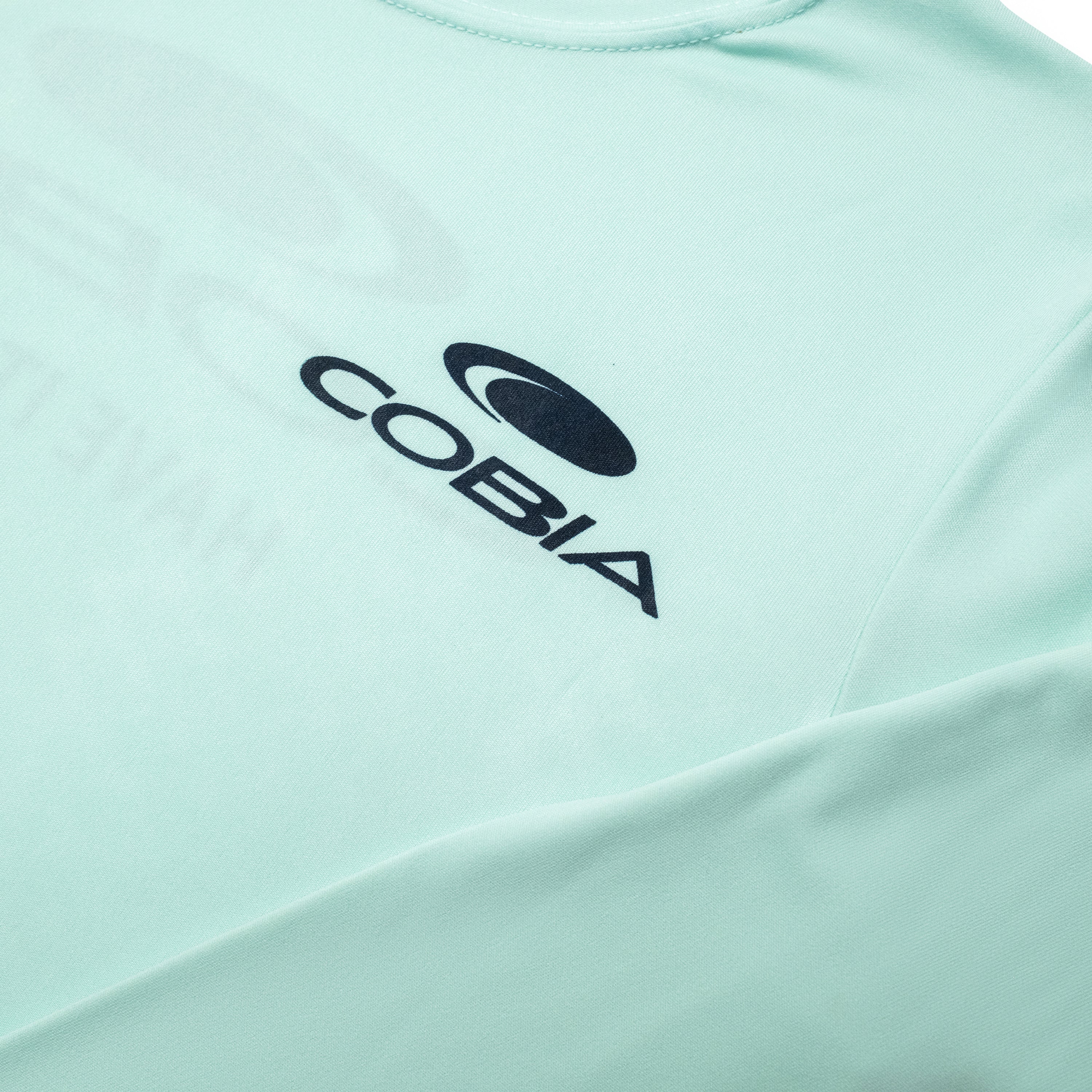 Close-up of a mint green shirt featuring the logo 'COBIA' on the front.