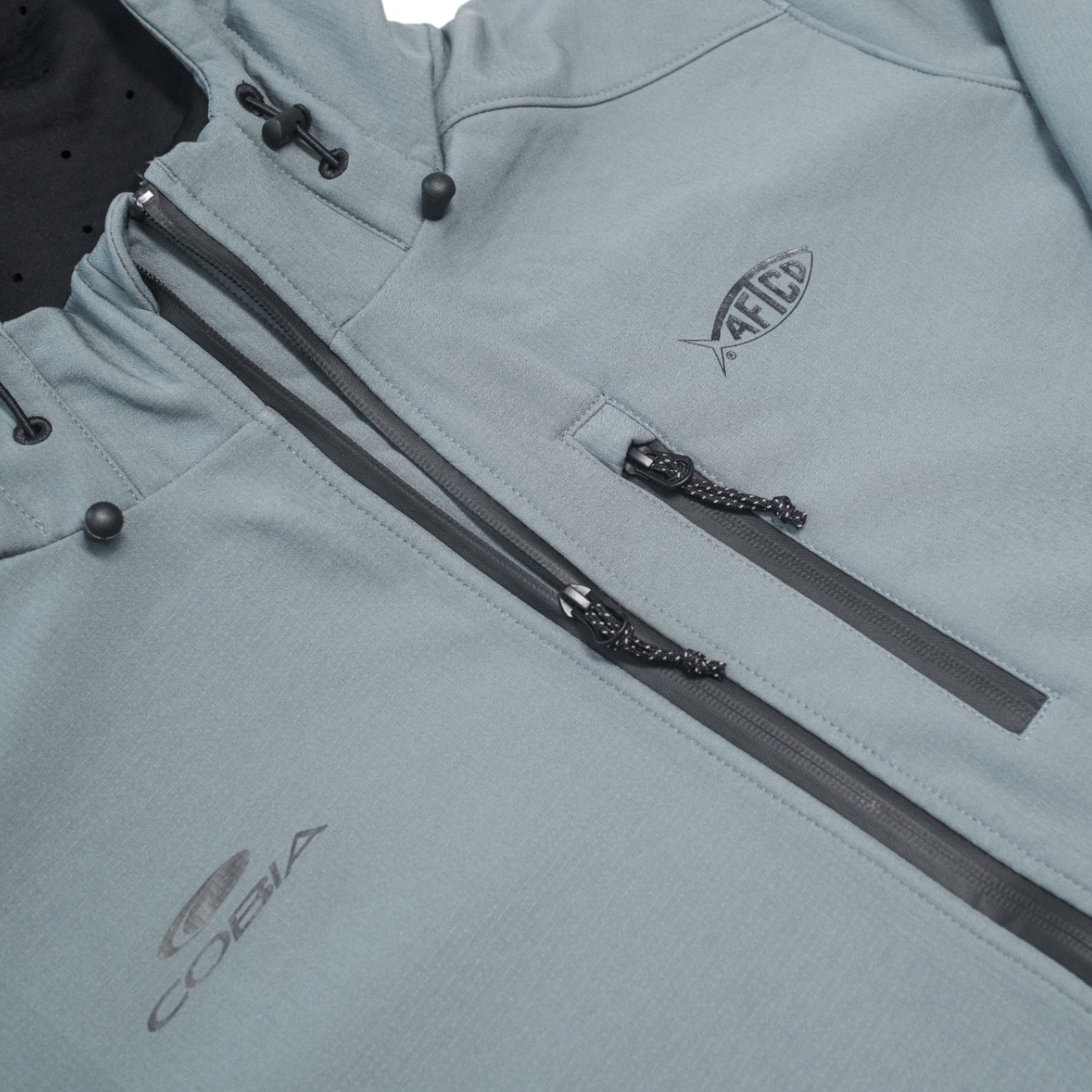 Close-up of a light grey jacket with zippers and logos on the chest.