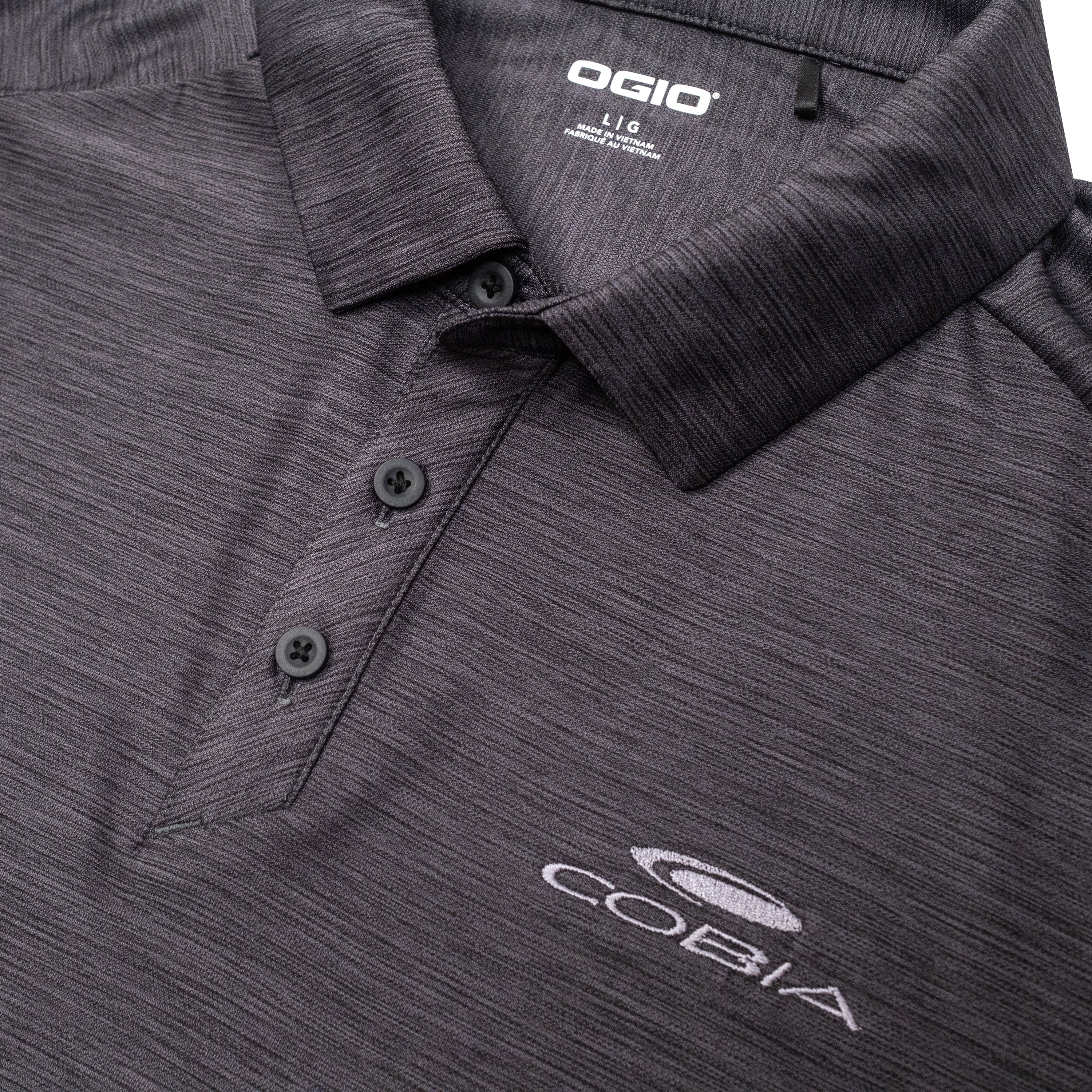 Close-up of a dark gray Ogio polo shirt with an embroidered COBIA logo.