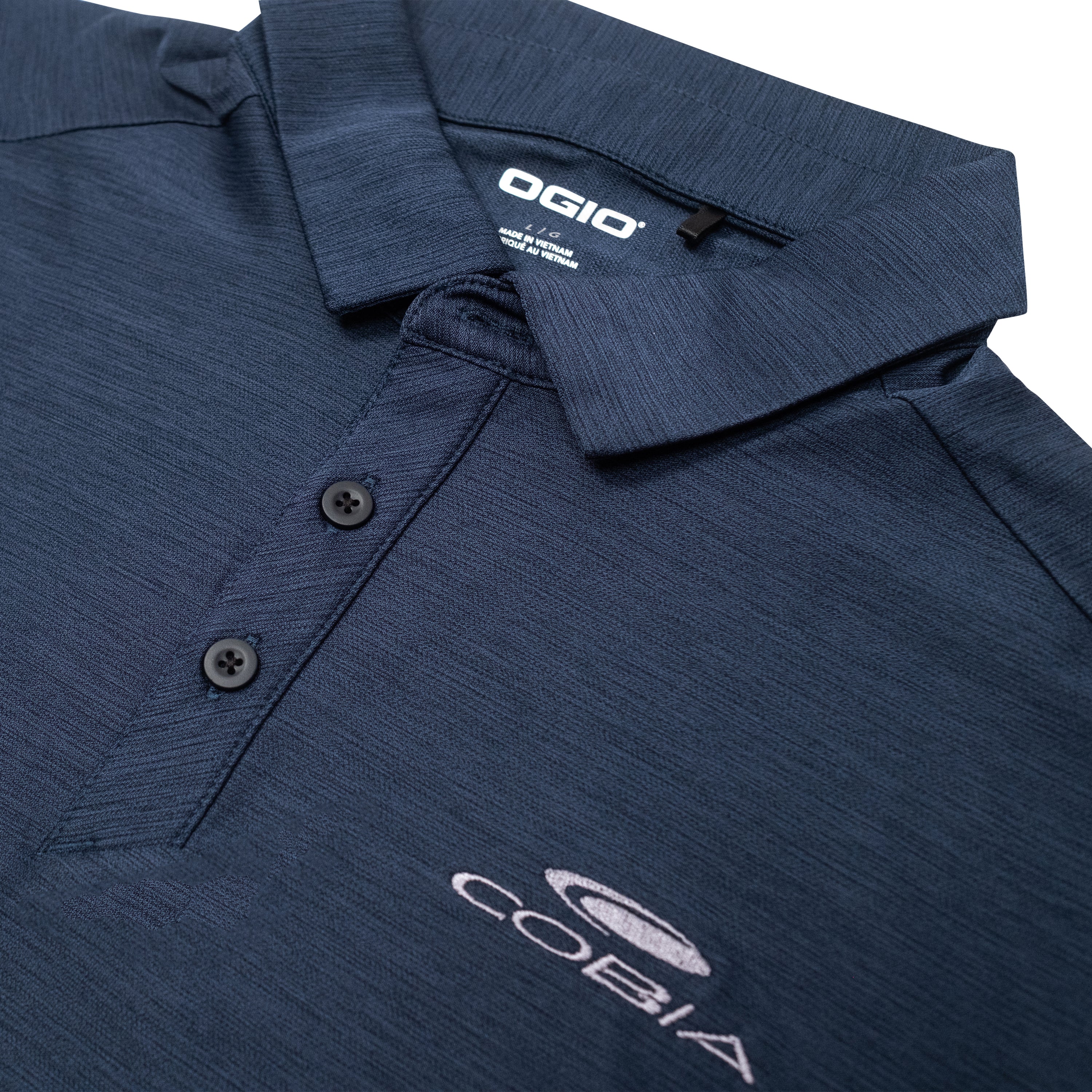 Close-up of a navy blue polo shirt with a collar and a white cobia logo.
