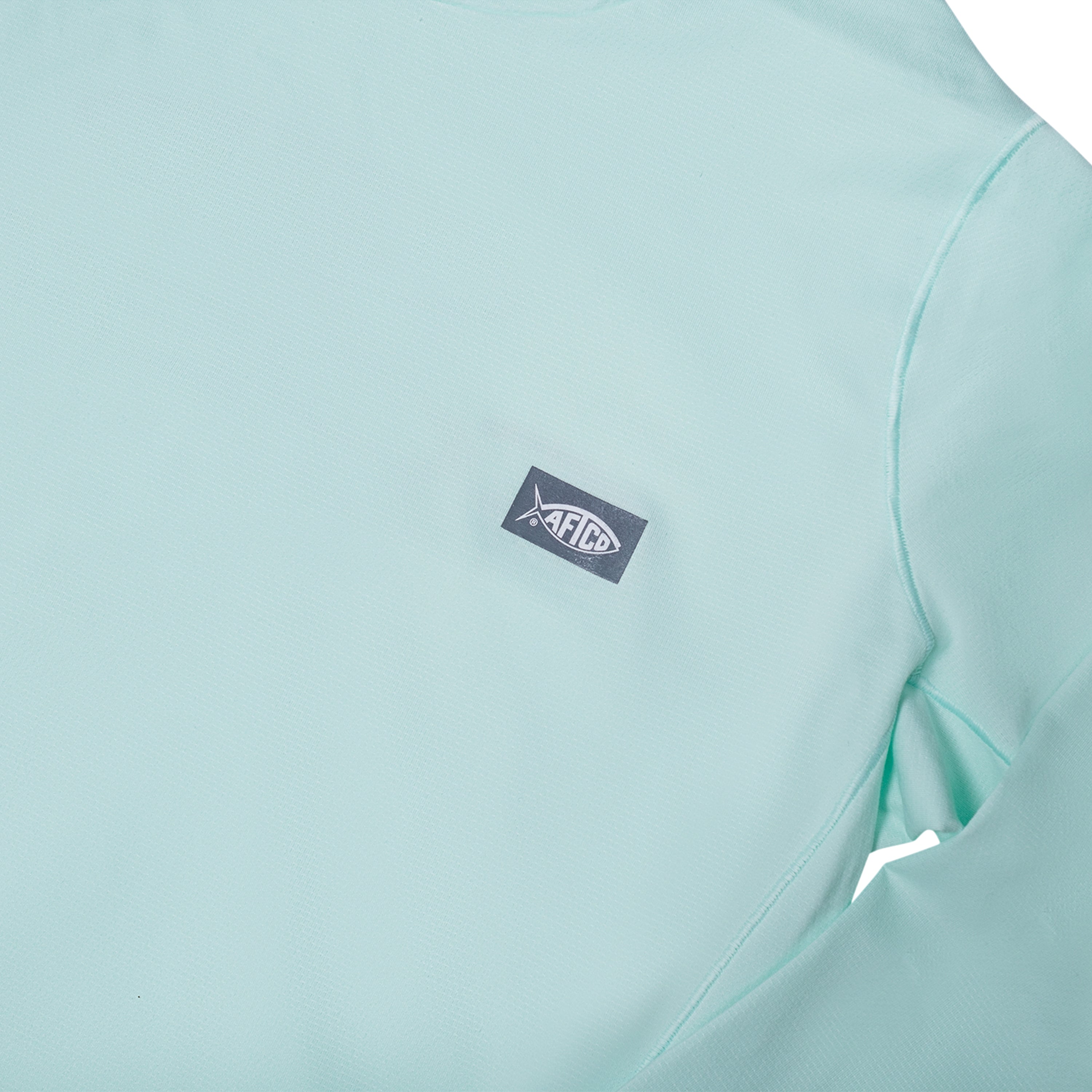 Close-up of a light mint green shirt with an aftco logo patch.