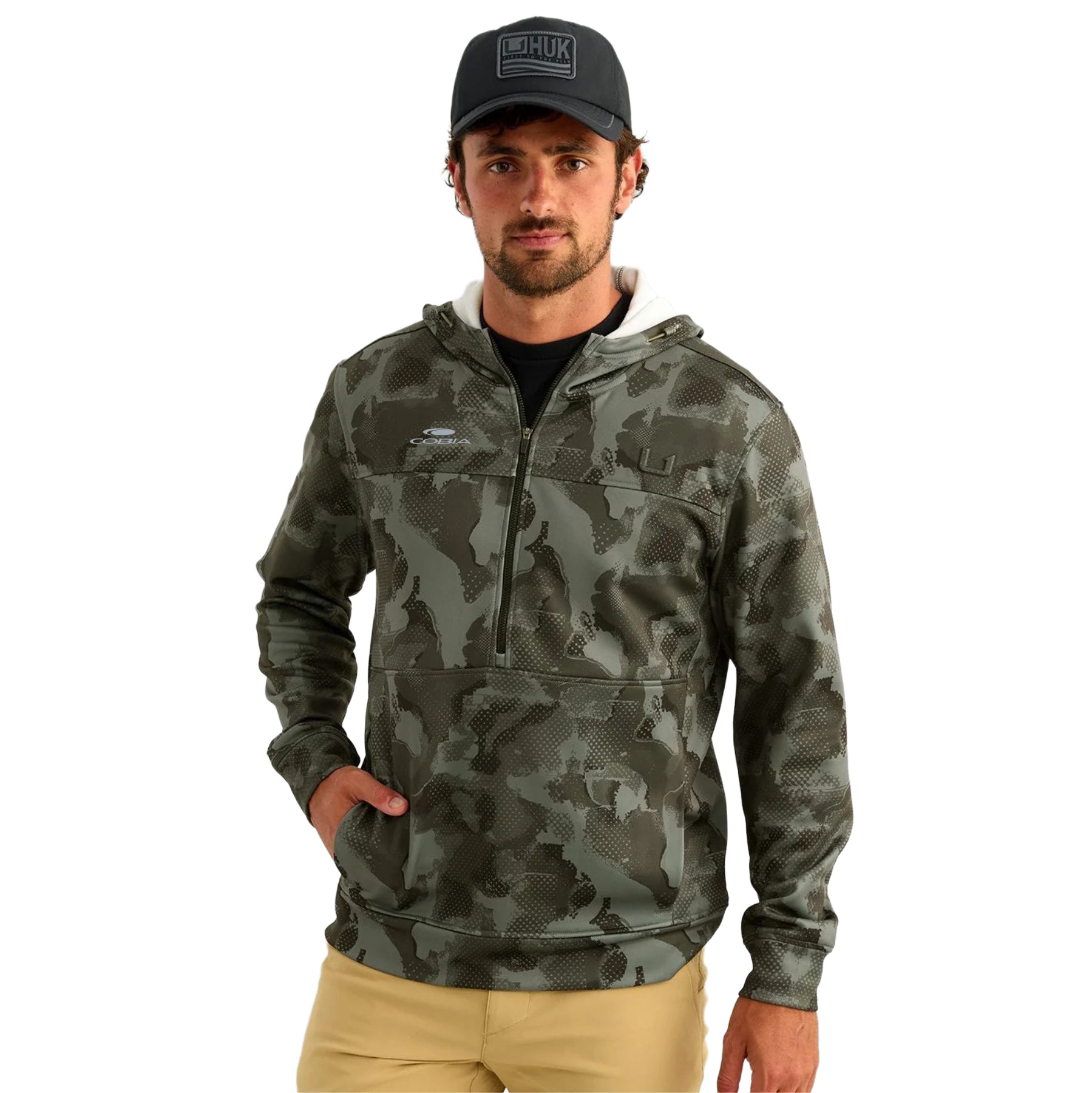 A man wearing a black hooded half-zip jacket with a digital camo pattern and a cobia logo on the right chest.