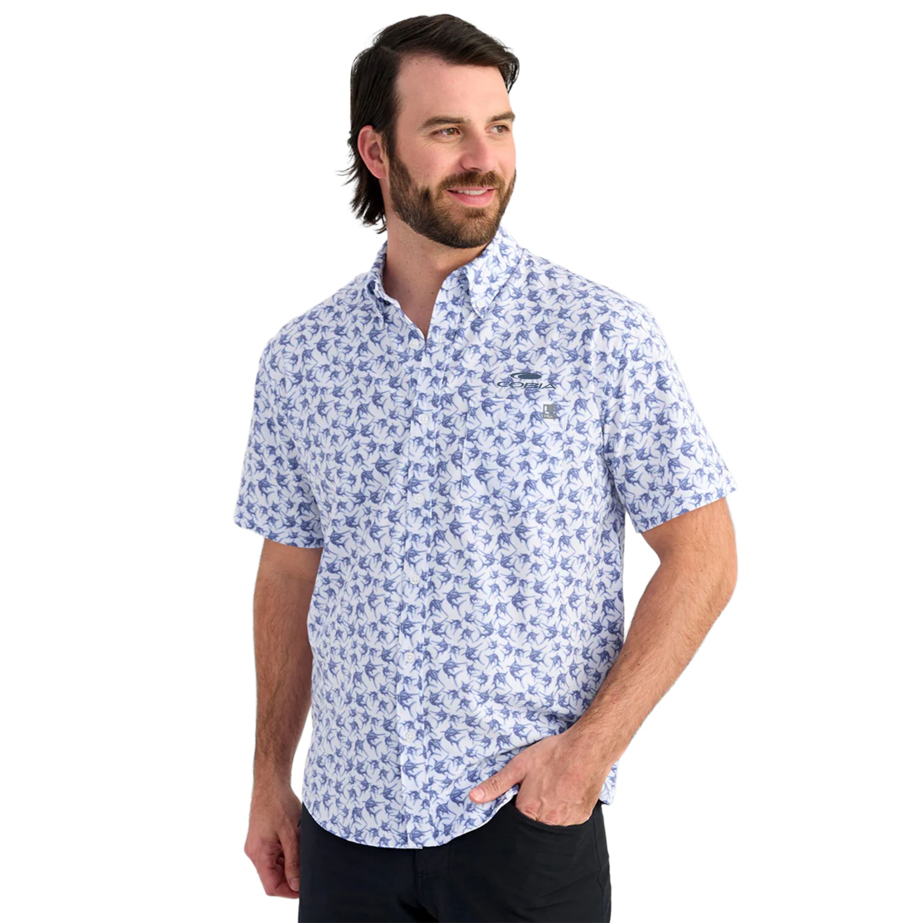 Man wearing a white short sleeve button down with a blue fish pattern across it, featuring a cobia logo on the chest.